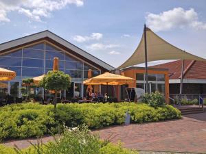 a building with tables and umbrellas in front of it at Ferienwohnungen Hinrichs in Carolinensiel