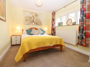 a bedroom with a bed with a yellow blanket at La'l Skaithe in Kirkby Stephen
