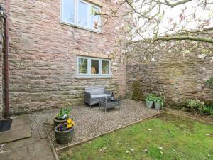a backyard with a bench and a brick building at La'l Skaithe in Kirkby Stephen