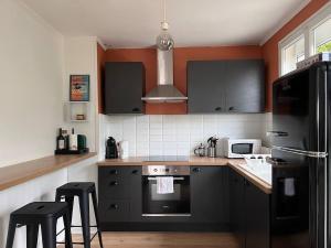 a kitchen with a black refrigerator and black cabinets at Villa clair de Falaises in Le Tréport