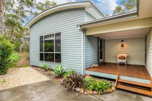 a house with a wooden porch with a chair on it at Triple B - Beach Bush Birds in Dunbogan