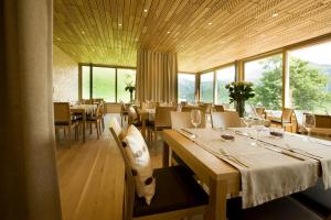 ein Esszimmer mit Tischen, Stühlen und Fenstern in der Unterkunft Hotel Alpenrose Ebnit in Dornbirn