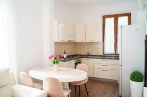 a kitchen with a white table and a white refrigerator at Siena COZY HOUSE in Siena