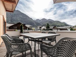 a table and chairs on a balcony with mountains at MYALPS Ötztal inklusive Spa- Area in Umhausen