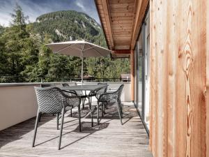 a patio with a table and chairs and an umbrella at MYALPS Ötztal inklusive Spa- Area in Umhausen