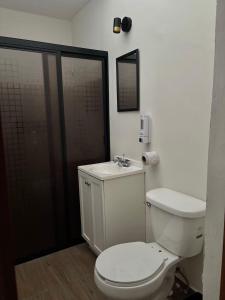 a bathroom with a white toilet and a sink at Loft K'iin in Campeche