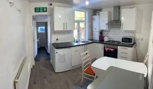a small kitchen with white cabinets and a table at The Ardens in Gillingham