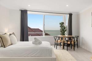 a bedroom with a bed and a table and a large window at Amazing Ocean View Studio at Bondi Beach in Sydney
