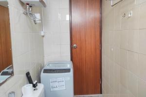a small bathroom with a washing machine and a wooden door at Spacious 2BR at Vida View Makassar Apartment By Travelio in Pampang +20 photos