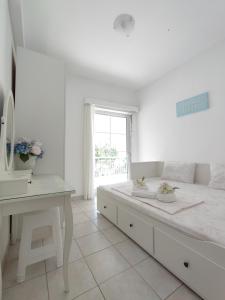 une chambre blanche avec un grand lit et un bureau dans l'établissement Lidia Apartments Nea Peramos 1, à Néa Péramos