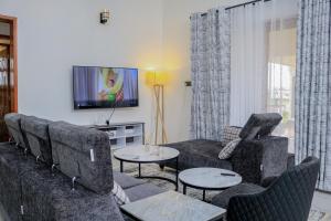 Una sala de estar con un sofá y sillas y un televisor. en Sweetwaters Holiday Home Nanyuki, en Nanyuki