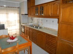 una cocina con armarios de madera, mesa y fregadero en Vila do Conde Holidays Flat, en Areia