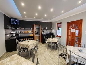 a restaurant with tables and chairs and a kitchen at Oázis Panzió in Makó