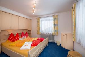 a bedroom with a large bed with red and orange pillows at Landhaus Vier Jahreszeiten in Krimml