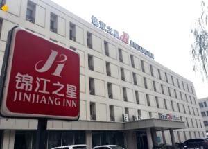 a red sign in front of a building at Jinjiang Inn Wuhan Optical Valley Finance Habour in Wuhan