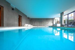 a swimming pool with blue water in a building at Studio-Hotel Apostroff in Koksijde