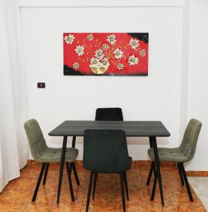 a dining room table with chairs and a painting on the wall at Aurora's Apartment Shkoder in Shkodër +71 photos