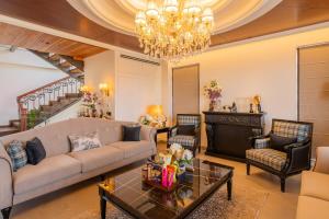 a living room with a couch and a chandelier at ELIVAAS privé The Royce Daisy Ultra-Luxe 4 BHK Villa with Pvt Heated Pool, Jacuzzi, Steam Room & Hill Views in Kasauli