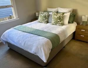 a bedroom with a large bed with green and white pillows at Eton Cottage - Central Boutique Stay in Toowoomba