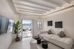 a living room with a white couch and a large window at Deliades Hotel in Ornos