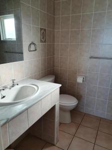 a bathroom with a sink and a toilet at Villa 26, Estuary Country Estate, Port Edward, KZN South Coast in Port Edward