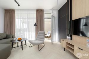 un salon avec un canapé et une télévision dans l'établissement Seaside Apartamenty Ku Morzu Sianożęty 150m to the beach, swimming pool, à Sianożęty