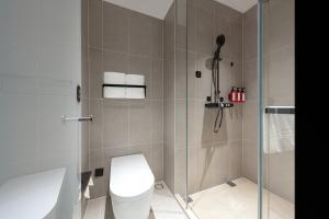 a bathroom with a toilet and a glass shower at Atour Light Hotel Wuhan Optics Valley Square Subway Station in Wuhan