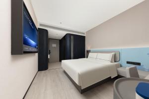a bedroom with a white bed and a flat screen tv at Atour Light Hotel Wuhan Optics Valley Square Subway Station in Wuhan