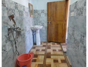 um banheiro com uma pia e uma porta de madeira em Atharva cottage, Joshimath em Jyotirmath