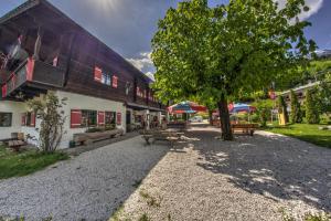 a building with benches and a tree in front of it at Wirtshaus und Pension Hocheck in Ramsau +16 photos