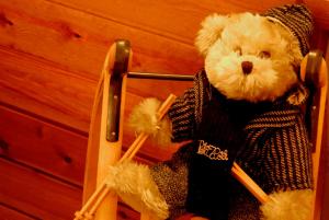 
a teddy bear sitting on a wooden chair at Petit Hotel in Pas de la Casa

