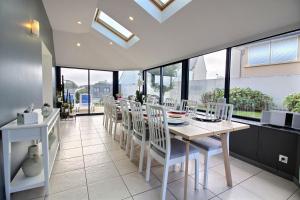 a dining room with a table and white chairs at Les pieds dans l'eau in Kerjagu