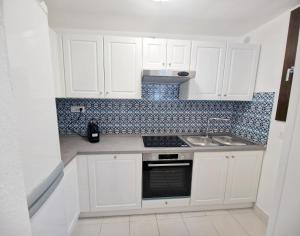 a white kitchen with white cabinets and a sink at Villa dell'Arte Vista Mare in Villasimius