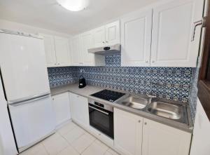 a white kitchen with a sink and a refrigerator at Villa dell'Arte Vista Mare in Villasimius