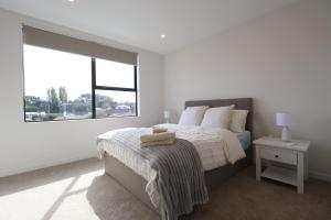 a white bedroom with a bed and a large window at Luxury Stay in Central Takapuna in Auckland