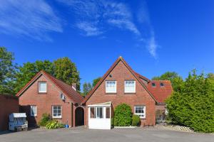 ein großes Backsteinhaus mit weißer Tür in der Unterkunft Ferienwohnungen und Ferienhaus Polmann in Nordwerdum in Werdum