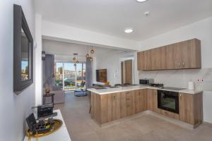 a kitchen with wooden cabinets and a living room at City Hall Suites in Limassol
