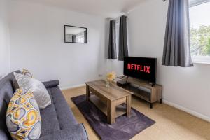 a living room with a couch and a tv at Stylish Home Near Addenbrookes Hospital by Traboule Properties Ltd in Shelford +6 photos