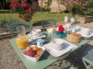 a green table with a bowl of fruit and a jug of orange juice at La Canolière - Chambre d'hôtes Camille in Sauveterre-Saint-Denis +2 photos