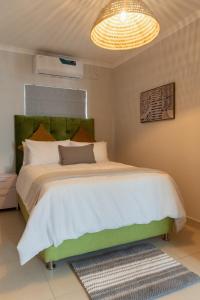 une chambre avec un grand lit avec une tête de lit verte dans l'établissement The Grazing Pad, à Gaborone
