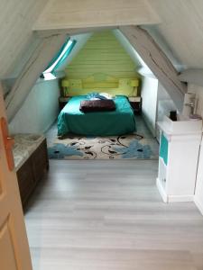 a bedroom with a green bed in an attic at Charmante petite maison proche de Meymac in Meymac
