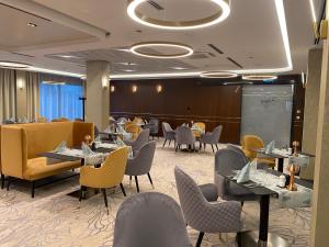 a restaurant with tables and chairs and people sitting at tables at Tisia Hotel & Spa in Tiszaújváros