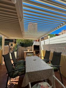 stół i krzesła pod markizą na patio w obiekcie Apartamento Barbacoa, Piscina y playa w mieście Puebla de Farnals