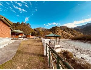 a fence with a gazebo next to a building at Alaknanda Adventure Resort and Rafting Camp in Nandaprayāg