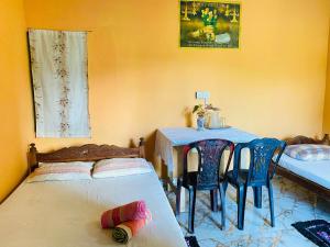 NikawatawanaChinna cottage的一间卧室，里面有一张床、一张桌子和几把椅子。