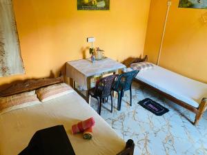 NikawatawanaChinna cottage的有两张床、一张桌子和几把椅子的房间 更多5张照片