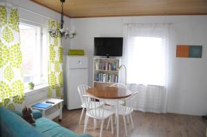 a living room with a table and chairs and a tv at Apartment Hotel Kuukkarin Kortteeri in Pori