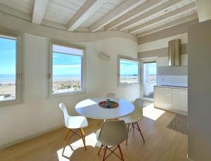 a white dining room with a table and chairs at Hotel Lux in Caorle