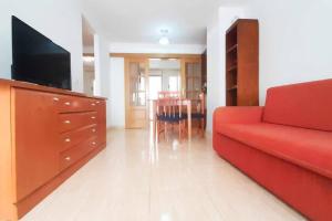 a living room with a red couch and a tv at Ayf confortable bajo de dos terrazas trebol dor in Oropesa del Mar