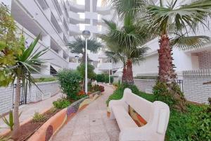 a lobby with white benches and palm trees in a building at Ayf confortable bajo de dos terrazas trebol dor in Oropesa del Mar